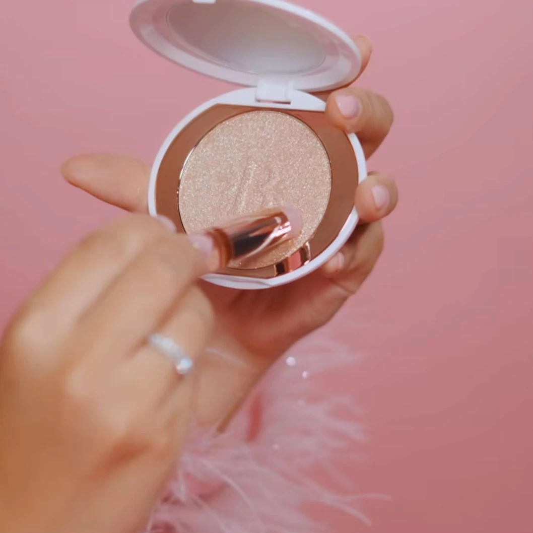 Brocha de silicona rosa con aplicador para iluminador en polvo dorado, parte de la colección Bloomshell.