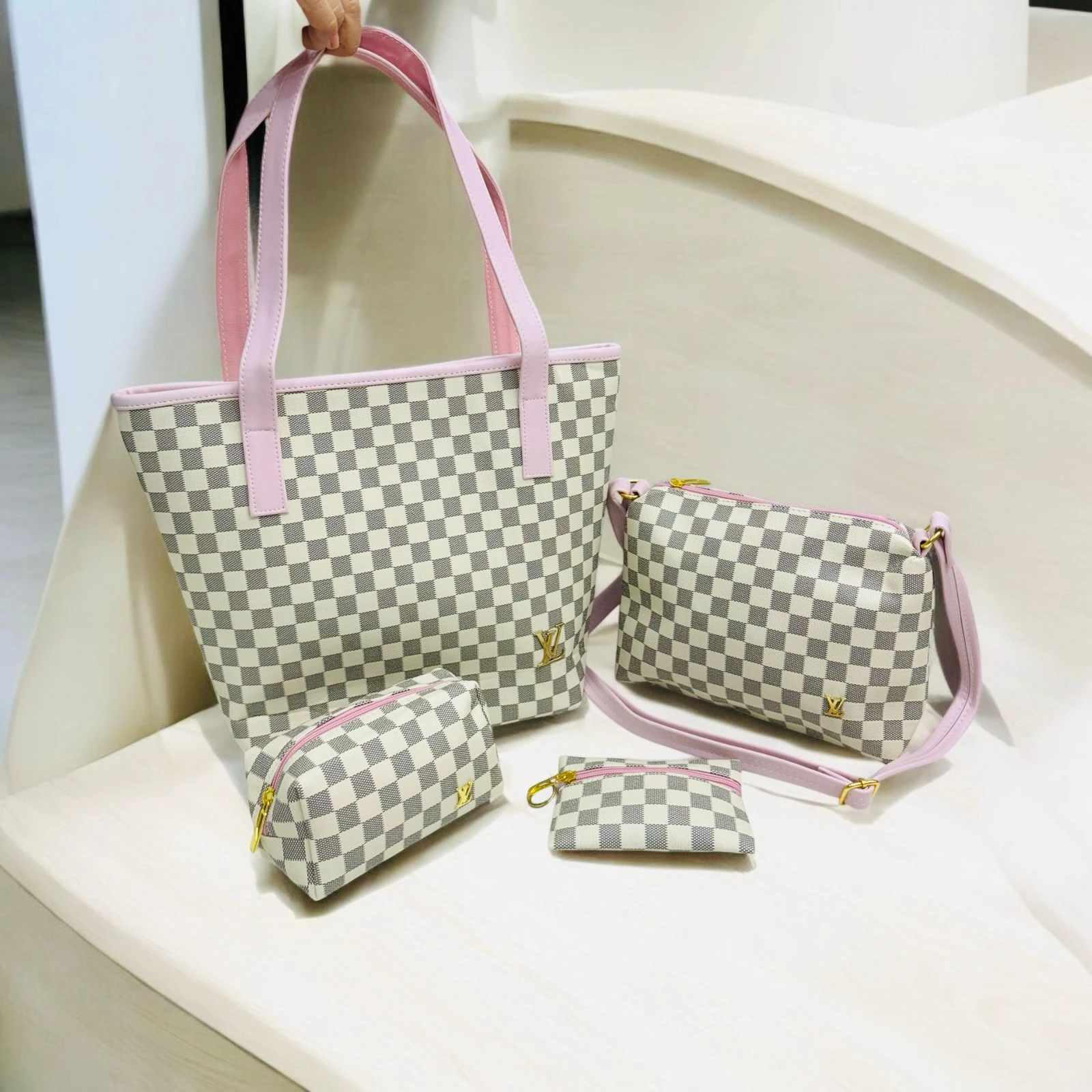 Set de cuatro bolsos Louis Vuitton Damier Azur con ribetes y correas color rosa pálido, sobre superficie blanca.
