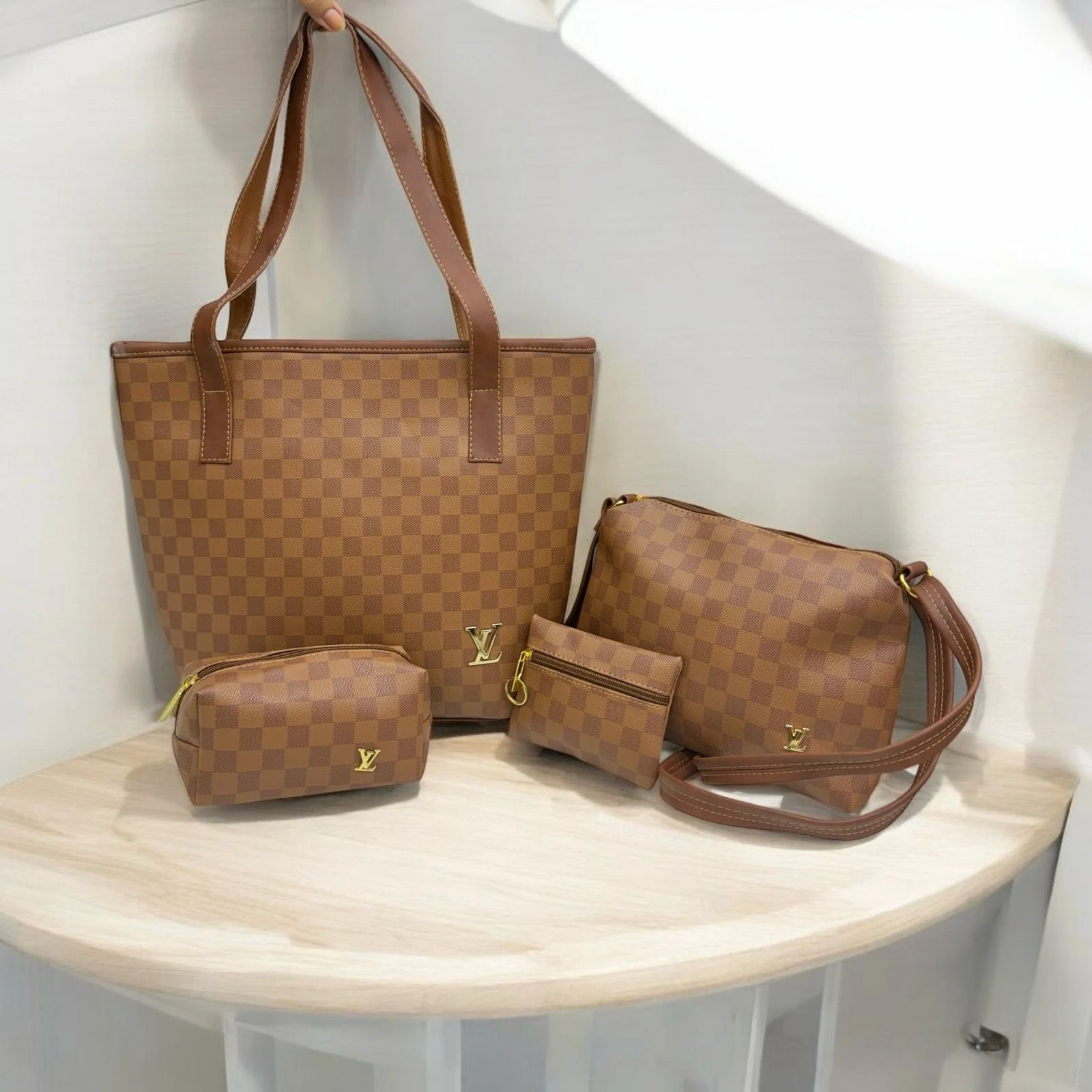 Set de cuatro bolsos marrones estilo Louis Vuitton Damier Ebene: un tote grande, una bandolera y dos monederos, sobre una superficie de madera clara.