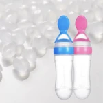 Dos cucharas dispensadoras de alimentos para bebés, una azul y otra rosa, hechas de silicona y plástico transparente.