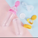 Cuchara dispensadora de silicona para bebé en rosa, blanco y amarillo, con frascos vacíos y tapas.