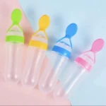Cuatro cucharas dispensadoras de silicona para bebés en colores verde, amarillo, azul y rosa sobre fondo bicolor.