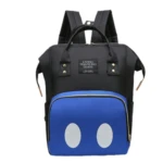 Morral pañalera negro con bolsillo frontal azul y dos círculos blancos, estilo Mickey Mouse.