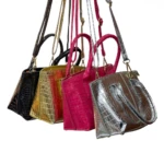 Bolso dama metalizado croco dorado, rosa, plata y negro colgando, asas y correa.