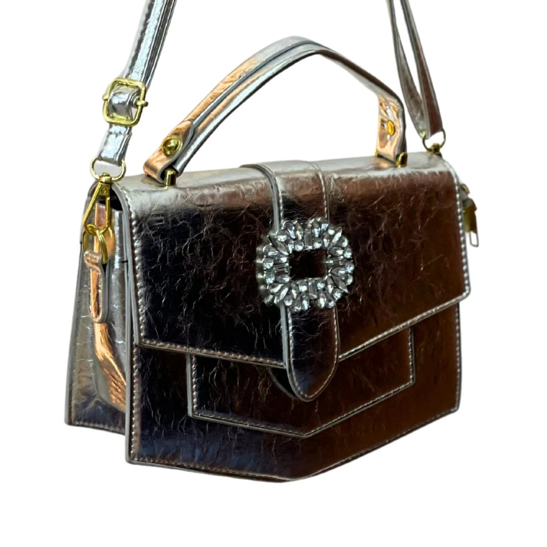 Bolso cartera pequeño plateado metalizado con textura arrugada, broche cuadrado con pedrería y correa ajustable.