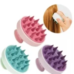 Cepillo masajeador capilar en colores rosa, turquesa y morado. Ideal para estimular el cuero cabelludo.