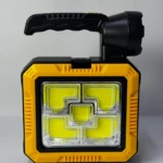 Linterna solar portátil amarilla y negra con manija plegable y múltiples paneles LED para camping y emergencias.