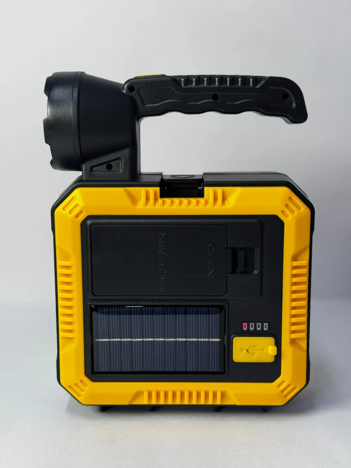 Linterna solar portátil amarilla y negra con asa, panel solar, puerto USB y luces indicadoras de carga.