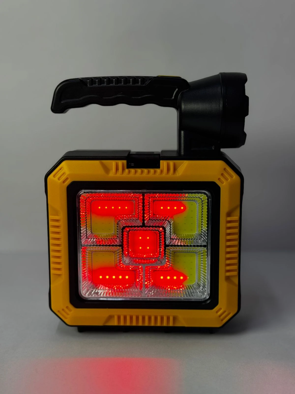 Linterna portátil amarilla y negra con luces LED rojas en el panel frontal y reflector.