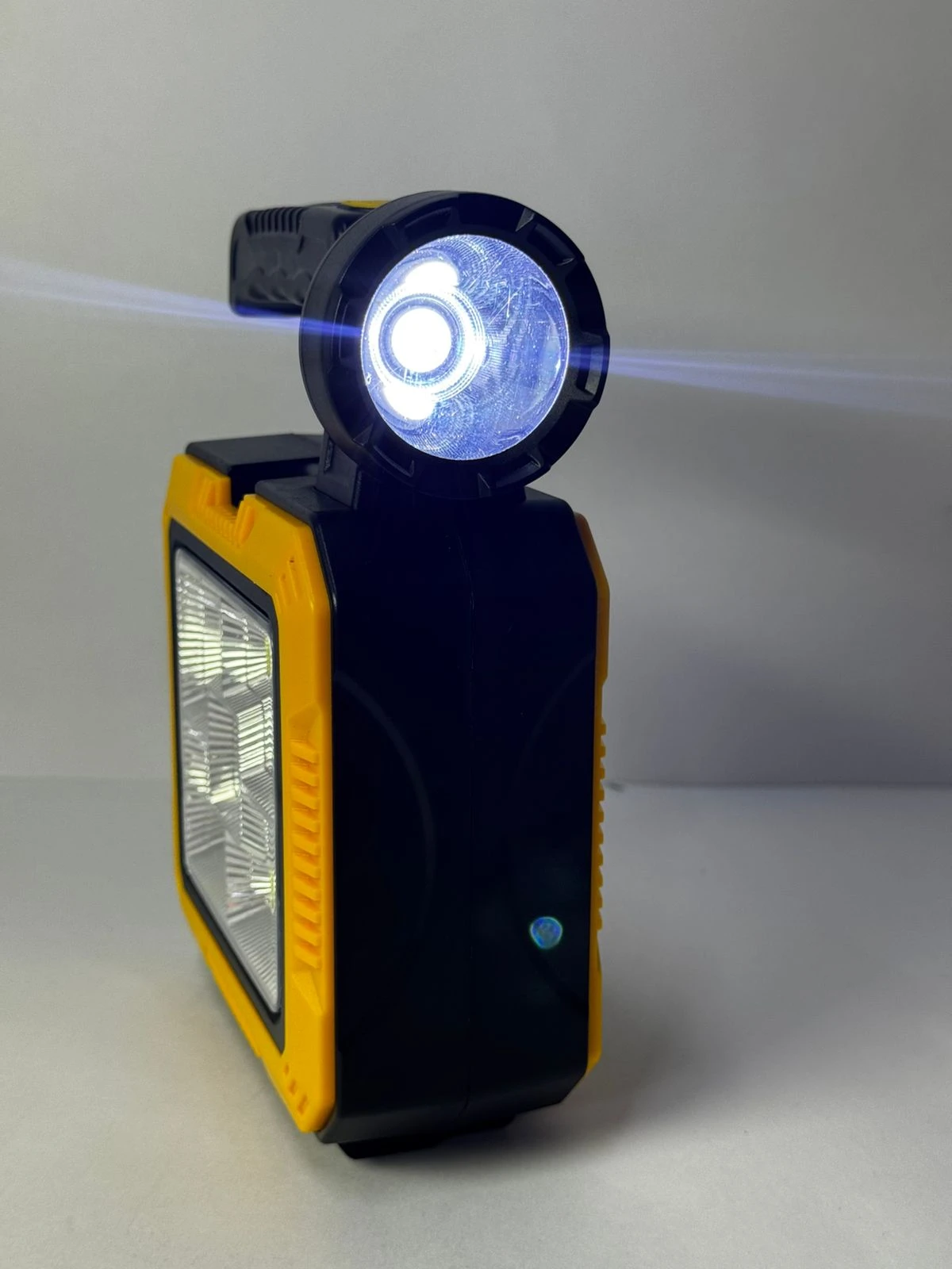 Linterna solar portátil amarilla y negra con panel de luz frontal, ideal para emergencias.