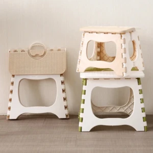 Tres taburetes plegables portátiles de plástico: uno cerrado color beige, dos apilados blancos con detalles en verde y beige.