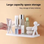 Repisa blanca de pared para baño con varios artículos de tocador y un muñeco blanco decorativo sujetándose.