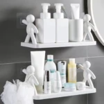 Repisa blanca para baño con figuras humanas decorativas, organizando botellas y cosméticos.