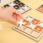 Juego de mesa triqui madera con fichas blancas X y anaranjadas O. Mano coloca ficha.