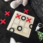 Juego de mesa triqui de madera con fichas rojas (X) y negras (O) dispuestas.