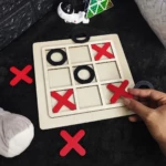 Juego de mesa Triqui de madera con fichas rojas y negras.