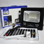 Lámpara solar Jortan de 200W IP66. Incluye caja, panel solar con cable, control remoto, baterías y tornillos de montaje dispuestos sobre una superficie.