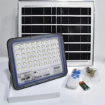 Lámpara solar Jortan 200W con panel rectangular, reflector LED, control remoto, baterías y kit de montaje metálico dispuestos sobre superficie blanca.