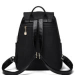 Bolso de dama y niña negro, de espalda con correas ajustables, detalles en piel y colgante dorado.