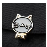 Pin metálico dorado y negro con diseño de gato y moño, adorno para bolso de dama o niña.