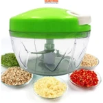 Picador de verduras manual verde con cuchillas, rodeado de cinco recipientes con ingredientes picados: perejil, nueces, ajo, cebolla y chile.