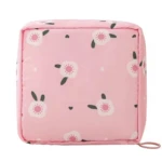 Cosmetiquera rosa cuadrada con estampado de flores blancas y detalles verdes.