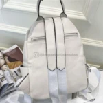 Morral blanco de dama con correas plateadas, cremalleras frontales y bolsillos laterales.