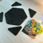 Juego de mesa Ajedrez Triangular con piezas de colores en bolsa, tableros hexagonales y triangulares negros.