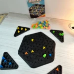 Juego de mesa ajedrez triangular con piezas de colores y tablero hexagonal.