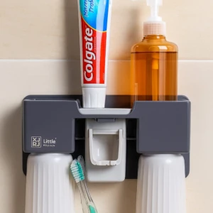 Organizador de baño gris con dispensador de jabón, pasta de dientes Colgate y cepillos dentales en vasos blancos.