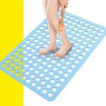 Alfombra de ducha azul con agujeros, una persona se frota la pierna con un cepillo de madera.