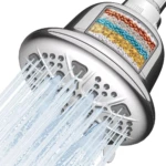 Ducha cromada de alta presión con cabezal filtrante translúcido que muestra capas internas de piedras minerales de colores para purificar el agua.
