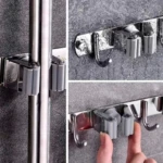 Soporte organizador acero inoxidable para escobas y trapeadores, mostrando mecanismo de agarre y ganchos.