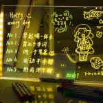 Tablero acrílico luminoso con mensajes y dibujos, ideal para escribir tareas o recordatorios diarios.