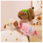 Pulseras de peluche capibara marfil, rosa y marrón con tortuga en la espalda, sujetas por manos.