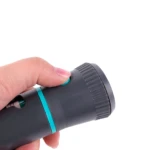 Mano sujetando dispensador de bolsas para perro con botón verde y banda turquesa.