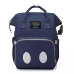 Morral pañalera azul marino con etiqueta "LIVING TRAVELING SHARE" y dos círculos blancos grandes abajo, estilo ratón.
