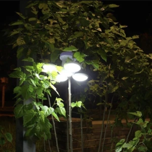 Lámpara solar expandible con 5 focos LED brillantes rodeada de hojas verdes en la noche.