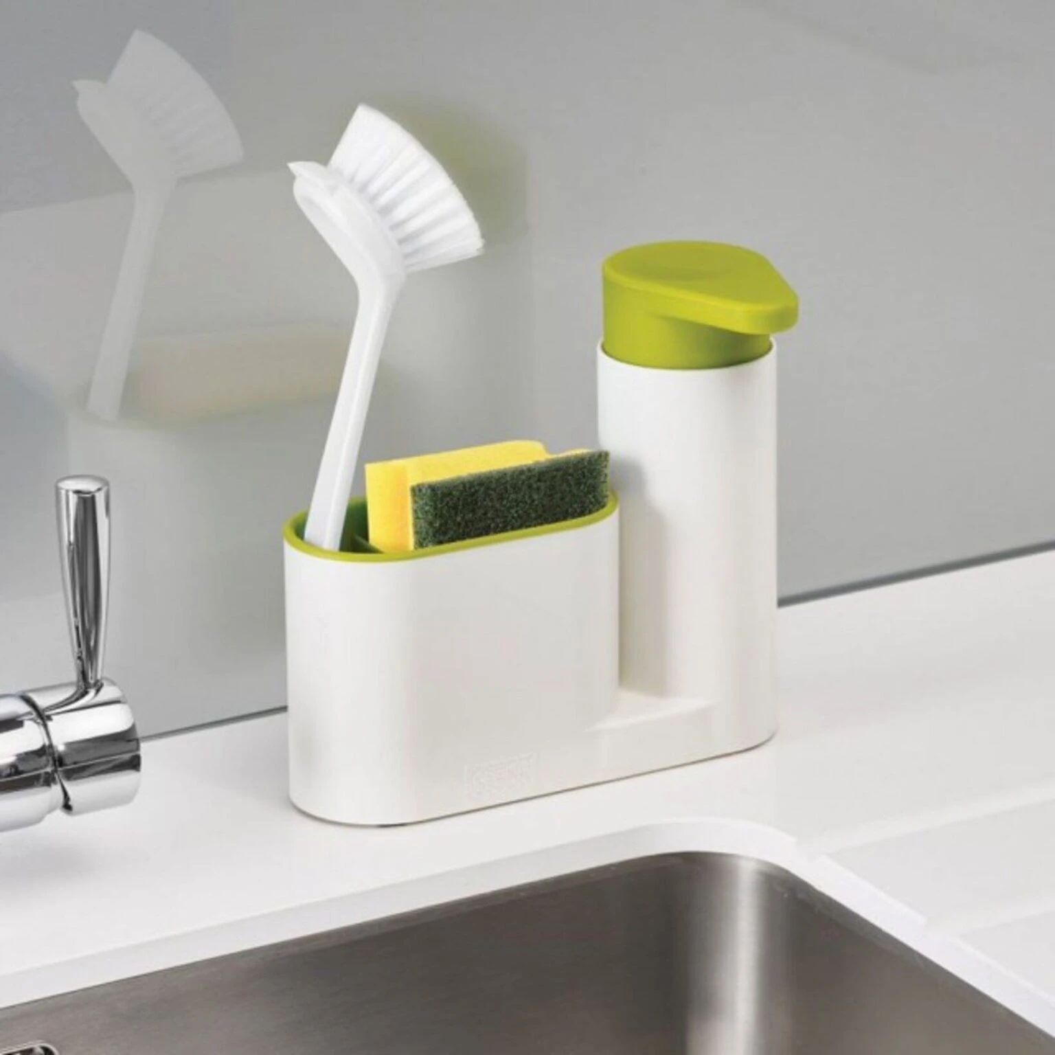 Dispensador de jabón blanco con tapa verde y organizador para cepillo y esponja de cocina.