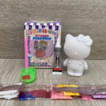 Set de pintura de diamante Hello Kitty blanca, caja morada, pegamento B-7000, aplicador y bolsitas con diamantes de colores.