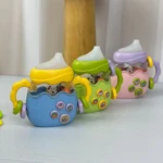Rascaencias didáctico tetero azul con sonajeros, botones musicales y figuras de animales.
