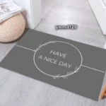 Tapete gris para baño con frase "Have a nice day" en blanco y borde decorativo, ideal para entrada.