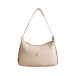Bolso de dama Karla Chacón Praga beige de cuero, con asa al hombro y detalle metálico al frente.