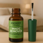 Frasco de vidrio ámbar de 15ml con etiqueta verde y tapa con aplicador integrado, junto a su tapa suelta, para remover esmalte en gel sobre mesa de madera.