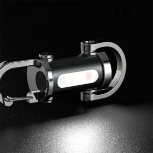 Linterna llavero compacta negra con detalles cromados, luz LED blanca encendida y puerto de carga USB lateral.