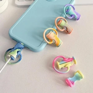 Protectores de cable para celular, estilo lazo, en colores tie-dye pastel, uno instalado en un cable azul claro.