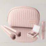 Neceser rosa acolchado con espejo, sombras, labial y brochas de maquillaje.