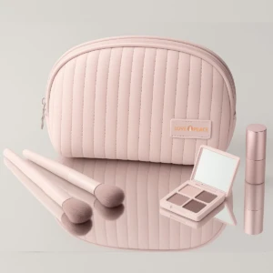 Neceser rosa acolchado con espejo, sombras, labial y brochas de maquillaje.