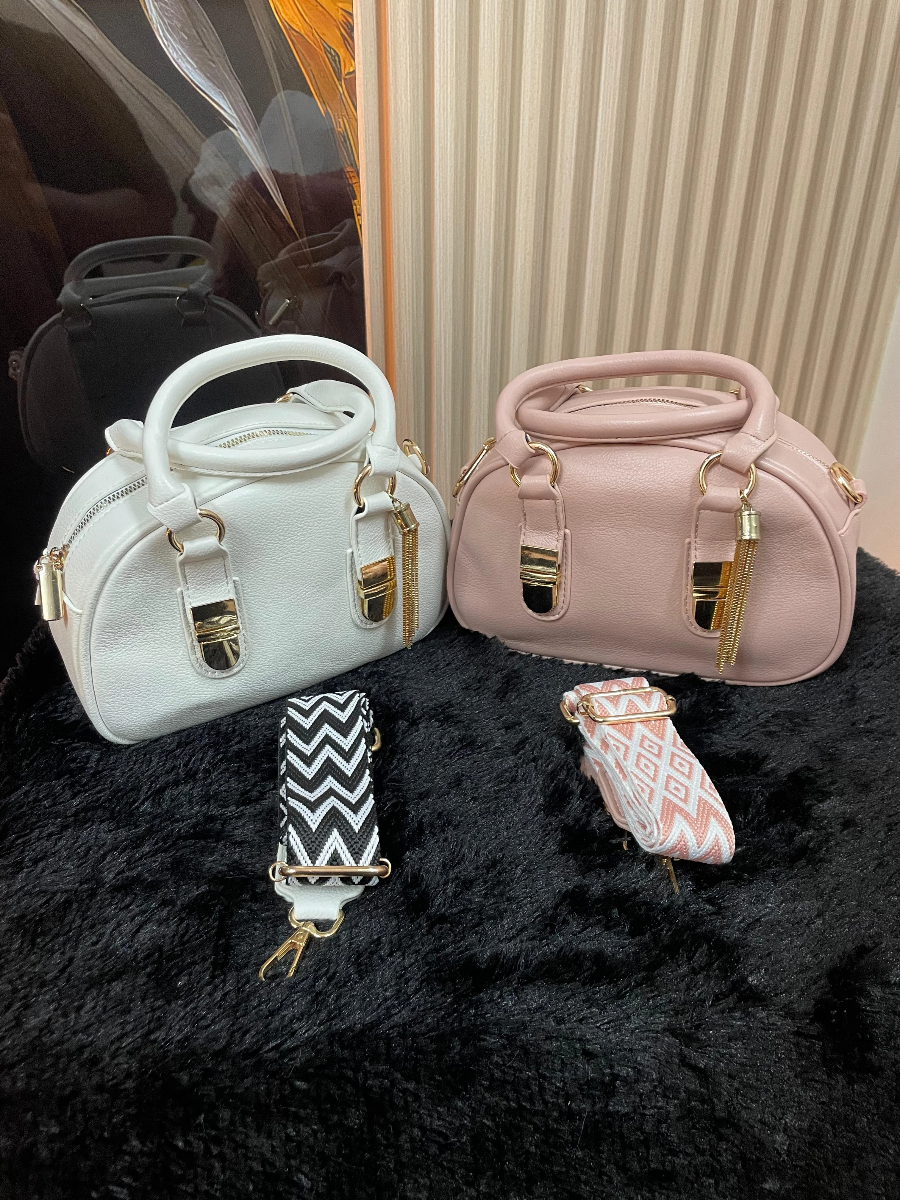 Bolsos redondos Gero-0198 blancos y rosas con correas intercambiables, sobre fondo negro.