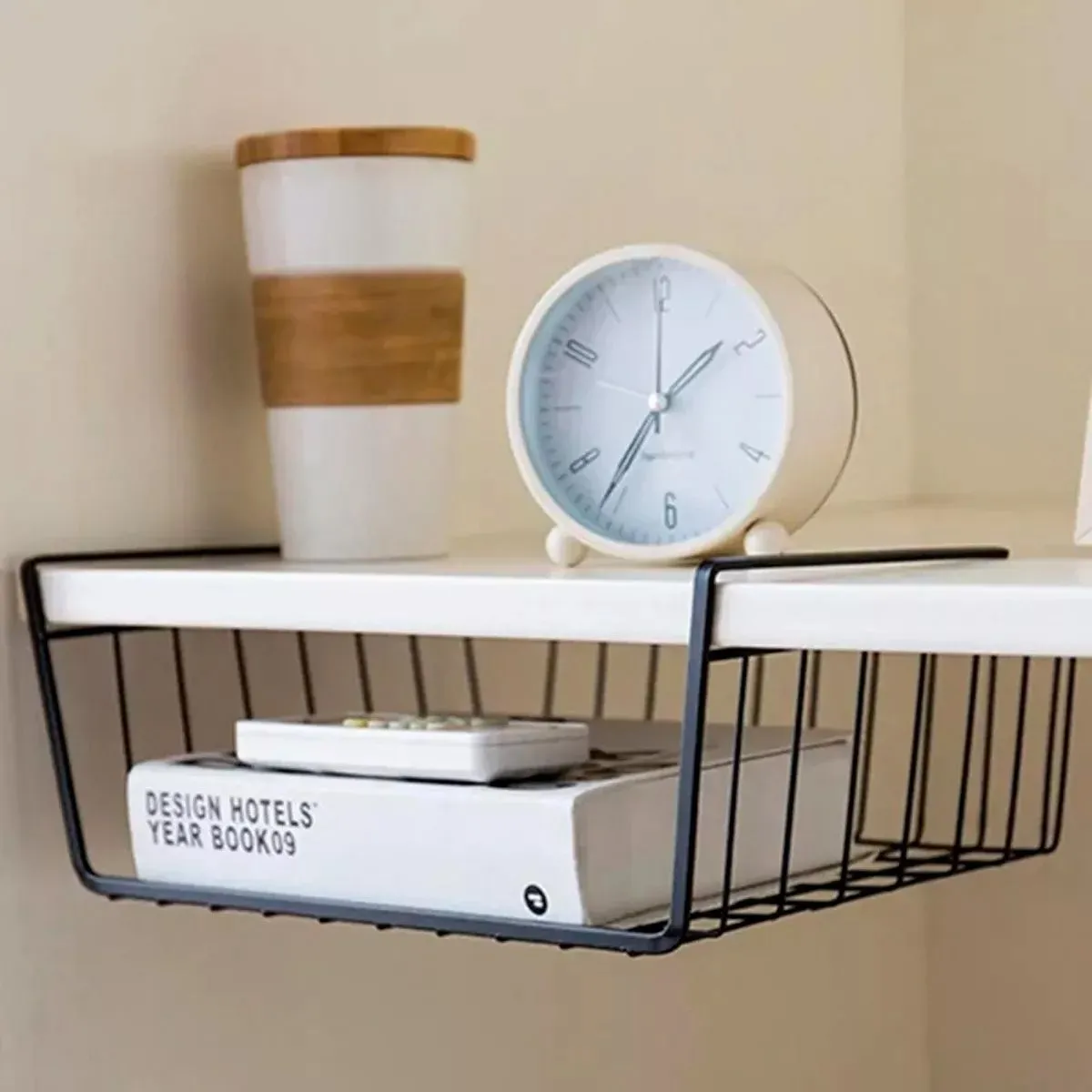 Organizador colgante de metal negro para repisa con taza y reloj en la parte superior y libro en la inferior.